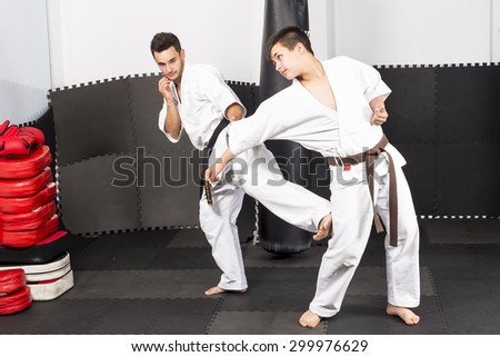 Two young men in kimono fighting during their training  in the gym