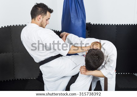Two young men in kimono fighting during their training in the gym