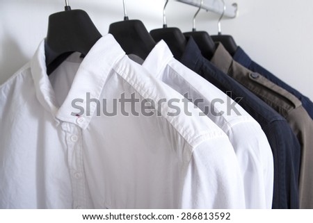 row of white and grey shirts hanging on coat hanger in white wardrobe