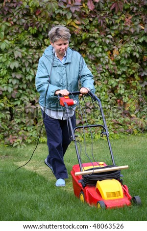 Middle Age Woman Mowing the Lawn