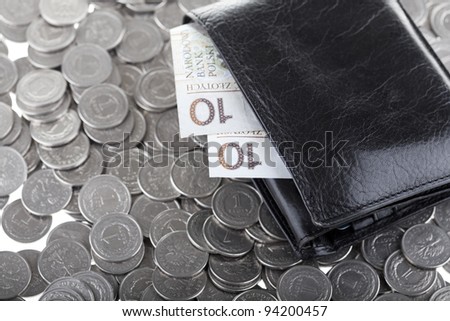 Black wallet with ten polish zloty paper money laying on one polish zloty coins. Money and savings concept.