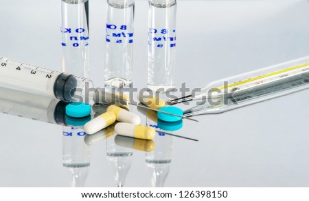 Medical vials, syringes and pills on a white background.