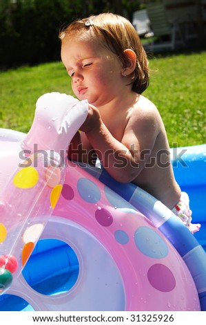 Cute girl playing in blue inflatable swimming pool
