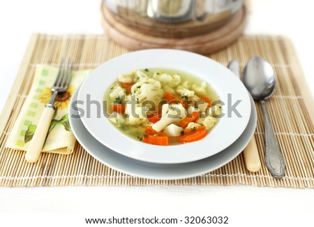 Vegetable soup with fork and knife and wooden tablecloth full isolated picture