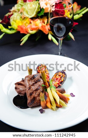 Juicy roe steak on a plate and glass of red wine