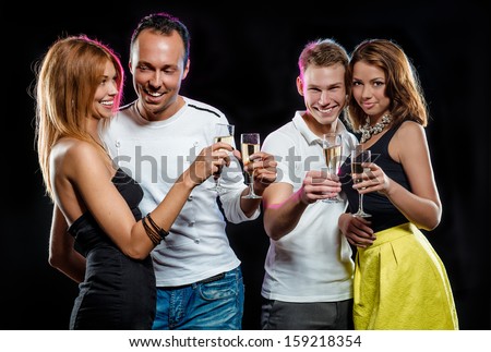 Cheerful group of young people with glasses of sparkling champagne over black background