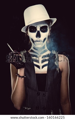 Woman with skeleton face art smoking over black background, conceptual photo