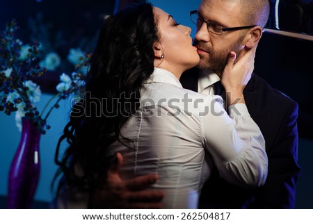 Kissing couple. Portrait of a sensual brunette and handsome businessman. Office romance concept