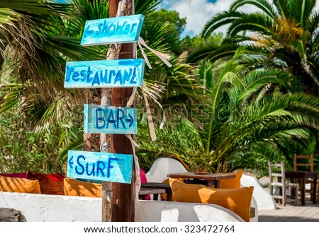 Signboard with arrows. Shower, bar, restaurant and surf directions on the Ibiza nudist beach. Balearic islands, Spain