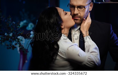 Kissing couple. Portrait of a sensual brunette and handsome businessman. Office romance concept
