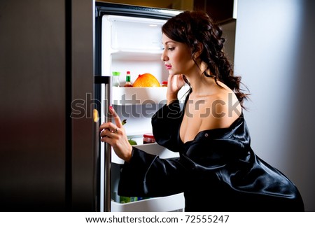 Young woman looking  for something to eat inside the fridge