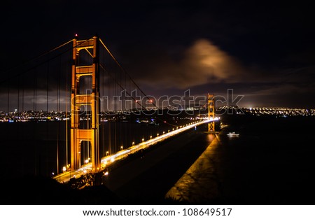 Beautiful  portrait of Golden Gate Bridge at twilight with subtle blue sky and golden hue of the bridge and San Francisco city visible on the far side.