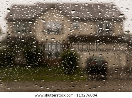 Nostalgia concept. House blurred behind curtain of raindrops