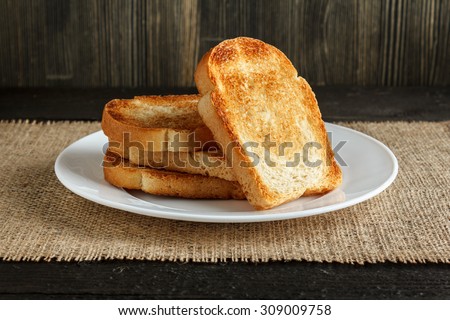 Dish with toasts on wooden table, covered by burlap close-up