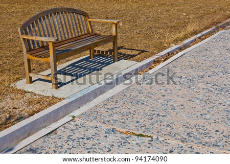 A lonely wooden bench along the path in the park
