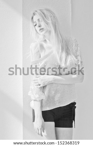 portrait of attractive girl posing against white wall. black-and-white photo