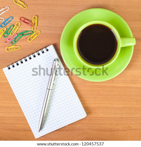 Coffee cup, notebook and pen on a desk