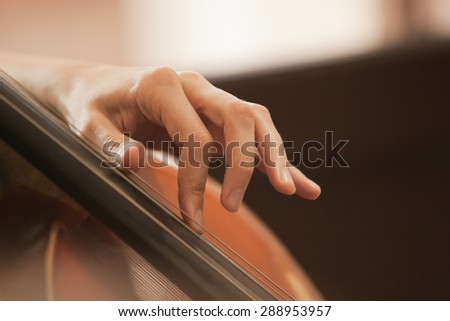 The woman\'s fingers on the strings of a cello