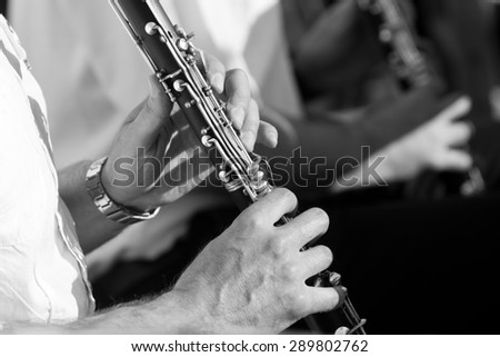 Hands of man playing the clarinet in black and white
