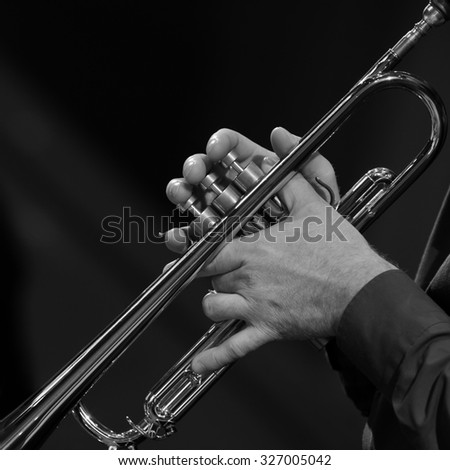 Hands of a man playing a trumpet in black and white