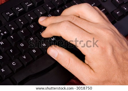 Well lit close up of a hand of a man on a computer keyboard. The keyboard is black and the hand is Caucasian /white.