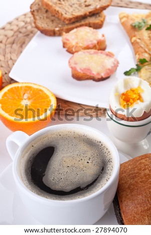 breakfast meal with a boiled egg, two pieces of toast, an orange and a cup of coffee