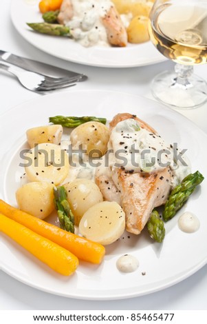 Baked chicken with creamy asparagus sauce served with potatoes and carrots