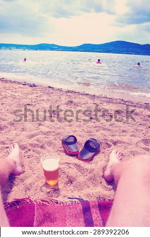 wet boy's feet on the beach and sand with cup of beer with instagram effect retro vintage filter