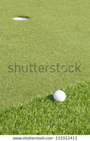 A golf ball near the hole on a green