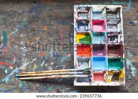 art palette with paint and brushes on wood background