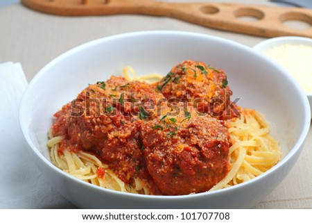 BIG MEATBALLS OVER LINGUINE - Beef meatballs in tomato sauce covered with Parmesan cheese & Italian parsley on linguine in a white china pasta bowl.