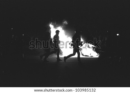 LOS ANGELES, CA - APRIL 29: LAPD officers in riot gear advance past burning police car on night one of the Rodney King Riots on April 29 1992 in Los Angeles, CA.
