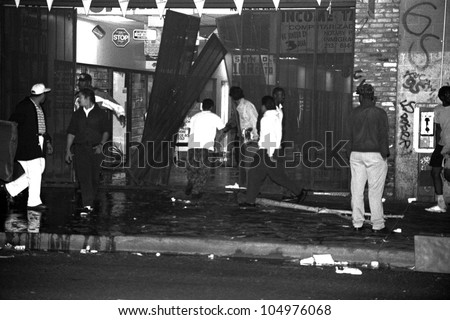 LOS ANGELES, CA - 29 APRIL 1992: Looters tear down storefronts on South Broadway in downtown Los Angeles during night one of the Rodney King Riots on 29 April 1992 in Los Angeles, CA.