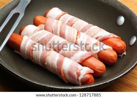 Wieners In A Blanket/Hot dogs wrapped in raw bacon in pan ready to be fried on cutting board