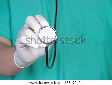 Man wearing surgical scrub shirt, stethoscope & Latex glove about to examine a patient