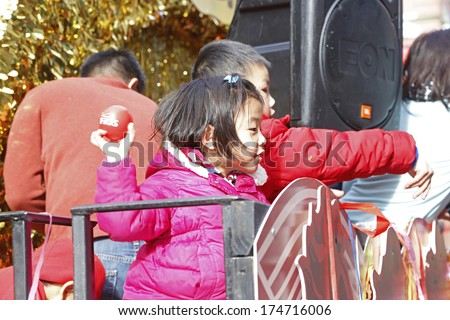 NEW YORK CITY - FEBRUARY 2 2014: Chinese Lunar New Year, the Year of the Horse, was celebrated by a parade in Manhattan's Chinatown. Young children toss FIOS balls to parade watchers from a float