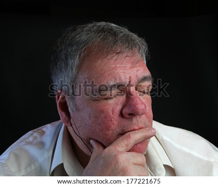 Middle age man with eyes closed listening to music on in ear monitors with dark background