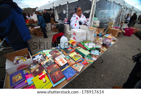 STATEN ISLAND, NEW YORK CITY - NOVEMBER 4 2012: Volunteers & national guard assembled at New Dorp High School to render aid to people recovering from Hurricane Sandy. Donated books for kids fill table