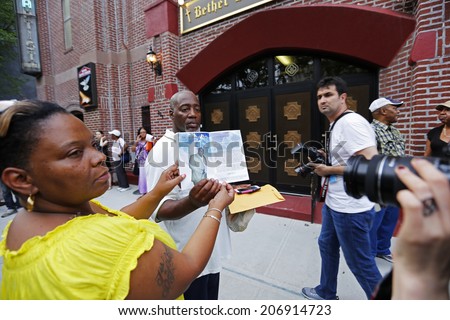 NEW YORK CITY - JULY 23 2014: Funeral services for Eric Garner, the Staten Island resident who died while being taken into custody by NYPD.Woman holding Eric Garner remembrance book before church