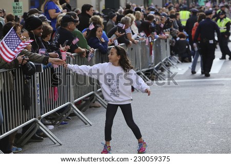 NEW YORK CITY - NOVEMBER 11 2014: the 95th annual Veteran's Day parade along Fifth Avenue is the largest Nov 11 celebration in the United States. Passing out US flags to spectators