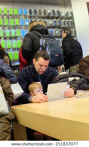 NEW YORK CITY - FEBRUARY10 2015: Apple closed the NYSE with a market capitalization of $705 billion dollars, the first company ever to breach $700 billion. Father introduces baby to technology.