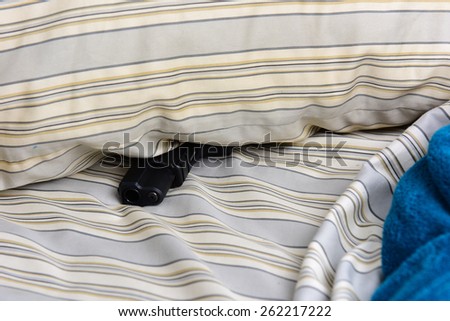 Bedroom security/part of automatic pistol sticking out from underneath pillow on unmade bed