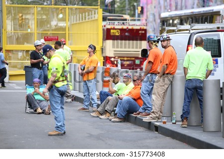 NEW YORK CITY - SEPTEMBER 11 2015: Memorial services were held at Ground Zero to mark the 14th anniversary of the World Trade Center attacks. Construction workers on break during moment of silence