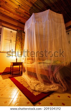 Mosquito net over a bed at night in the tropics