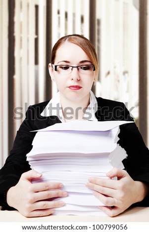 woman at her desk looking at all the paper work she has to do
