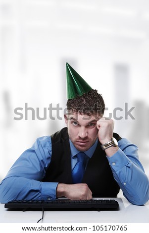 businessman wearing a party hat sitting at his desk