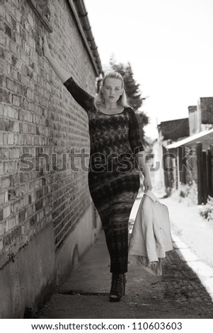 sexy high fashion shot of woman standing in a side street