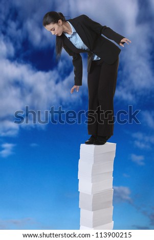 business woman standing on a very large stack of paper work, going high up into a sky  and she looking down at the earth below her