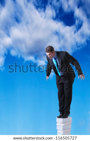 businessman standing on a large pile of paper going right up into the sky