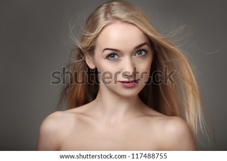 beauty headshot of sexy woman with bare shoulders and her blonde hair blowing